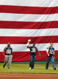 New England Patriots Super Bowl Champions Troy Brown (80), Lawyer Milloy (36), and quarterback Tom Brady, right, come out from the giant flag onto the field with the Super Bowl trophy prior to the start of the Boston Red Sox game against the Toronto Blue Jays at Fenway Park on opening day, Monday, April 1, 2002. (AP Photo/Winslow Townson) 