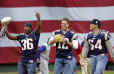 New England Patriots Superbowl Champions Lawyer Milloy (36), left, holding the Super Bowl Trophy, quarterback Tom Brady, center, and Ted Bruschi, right, come out from behind a giant American flag onto the field at Fenway Park in Boston, prior to the start of play against the Toronto Blue Jays on opening day, Monday, April 1, 2002. (AP Photo/Elise Amendola) 